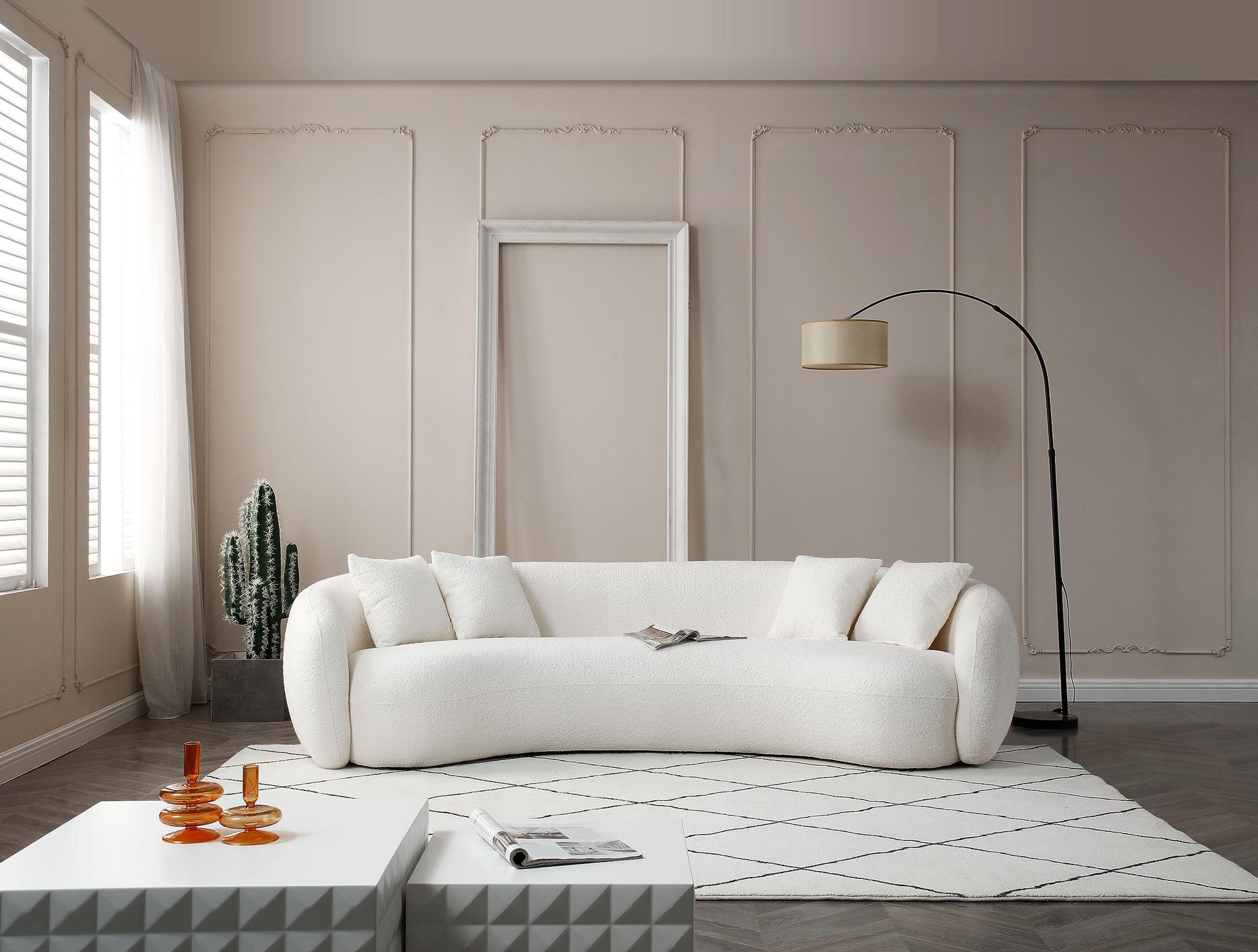 Modern living room with white curved sofa, cactus plant, geometric tables, and floor lamp