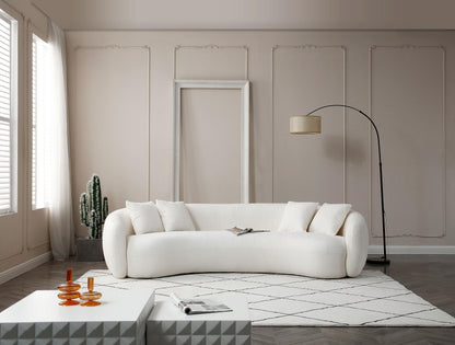 Modern living room with white curved sofa, cactus plant, geometric tables, and floor lamp