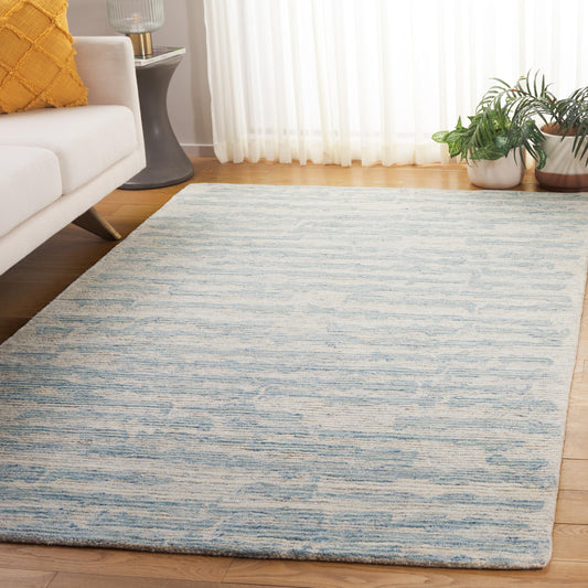 Modern living room with light blue patterned area rug, cream sofa, and houseplants